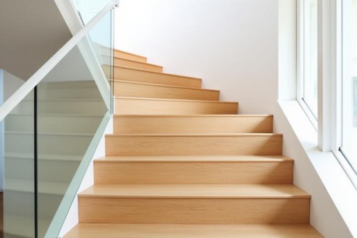 Modern wooden staircase with clear glass panels instead of traditional balusters, allowing maximum light